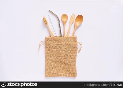 Flat lay of sustainable products, wooden spoon, stainless straw in natural sack bag on white background, eco friendly and zero waste concept