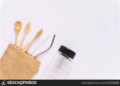 Flat lay of sustainable products, wooden spoon, stainless straw in sack bag with bottle on white background and copy space, eco friendly and zero waste concept