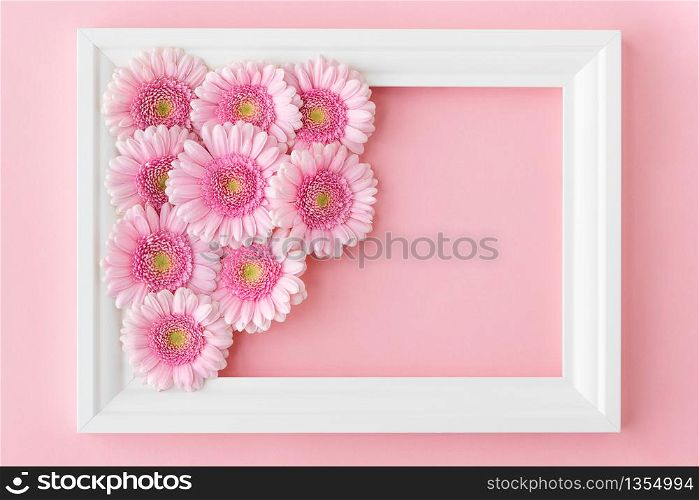 Flat lay of white frame with pink flowers gerberas on pastel pink background, copy space. Happy Mother&rsquo;s Day, Women&rsquo;s Day, Valentine&rsquo;s Day or Birthday. Spring greeting card.