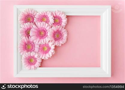 Flat lay of white frame with pink flowers gerberas on pastel pink background, copy space. Happy Mother&rsquo;s Day, Women&rsquo;s Day, Valentine&rsquo;s Day or Birthday. Spring greeting card.