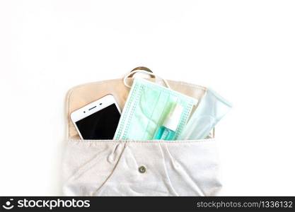 Flat lay of woman pouch with smart phone, sanitizer, alcohol spray and protective face mask. Protection Coronavirus/ Covid-19 and Air pollution pm2.5 concept. Top view with copy space.