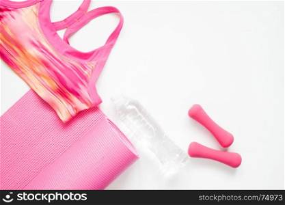 Flat lay of woman sport and yoga equipments in pink color on white background with copy space