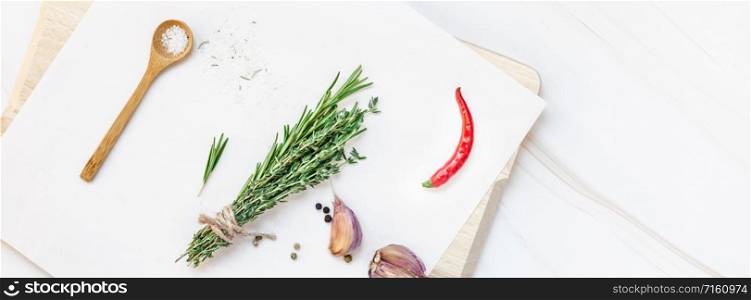 Flat lay overhead top view of greens herbs and spices on wooden cutting board on white marble background with copy space. Menu frame design food pattern background with cooking ingredients