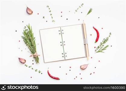 Flat lay overhead view blank notebook pages mockup text space invitation card on white background with greens herbs and spices. Menu or recipe book or food blog design with cooking ingredients