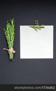 Flat lay overhead view blank recipe paper page with clip mockup text space invitation card on black background with greens herbs and spices. Menu recipe book food blog design with cooking ingredients