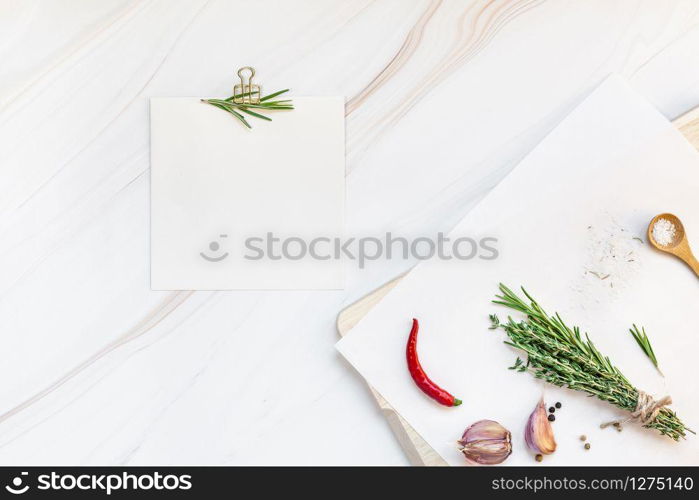 Flat lay overhead view blank recipe paper page with clip mockup text space invitation card on marble background with greens herbs and spices. Menu recipe book food blog design with cooking ingredients