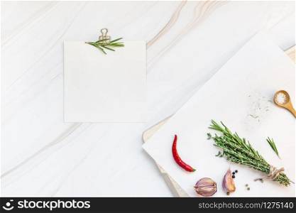 Flat lay overhead view blank recipe paper page with clip mockup text space invitation card on marble background with greens herbs and spices. Menu recipe book food blog design with cooking ingredients