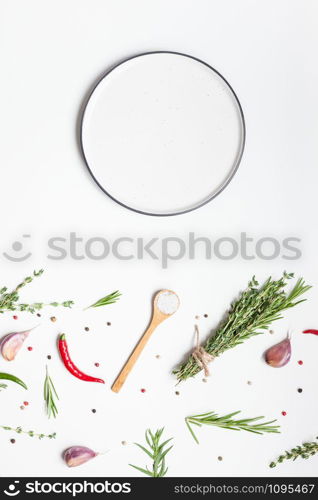 Flat lay overhead view empty plate mockup blank text space invitation card on white background with greens herbs and spices. Menu design food background with cooking ingredients