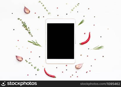 Flat lay overhead view tablet PC gadget mockup blank text space on white background with greens herbs and spices. Menu design food blog recipe cookbook or delivery app with cooking ingredients