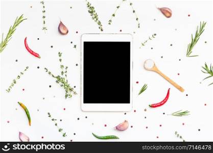 Flat lay overhead view tablet PC gadget mockup blank text space on white background with greens herbs and spices. Menu design food blog recipe cookbook or delivery app with cooking ingredients