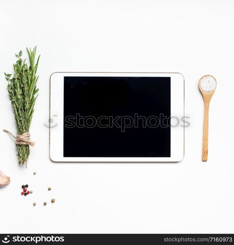 Flat lay overhead view tablet PC gadget mockup blank text space on white background with greens herbs and spices. Menu design food blog recipe cookbook or delivery app with cooking ingredients