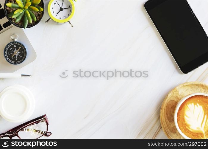 Flat lay photo in top view of business accessories, mobile, alarm clock, laptop, coffee, glasses and compass on white marble table with free copy space for text. Business and technology concept.