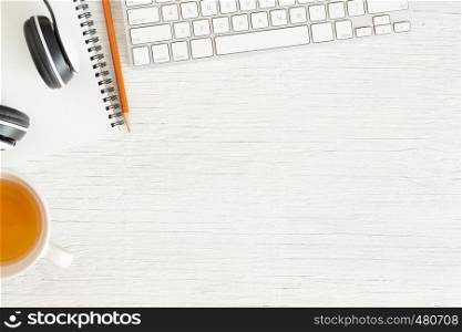 Flat lay photo of office desk with Earphone and keyboard,Copy space on white background with notebook and pencil, tea, Top view