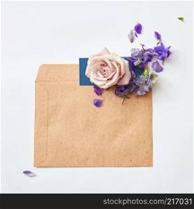 Flat lay shot of flowers and eco paper envelope on white background. Flowers in envelope