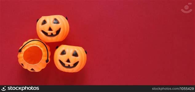 Flat lay style of halloween party concept with decorative plastic pumpkins on red background, copy space with banner style for text and template