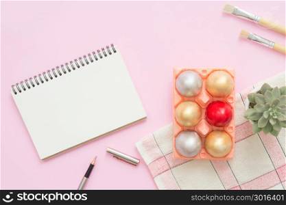 Flat lay top view colorful easter egg painted in pastel colors composition and mock up blank notebook with paint brush on pink pastel color background. Easter day background top view with copy space.