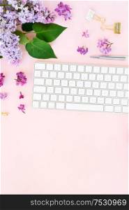 Flat lay top view home office workspace - modern keyboard with lilac flowers and copy space on desk. Top view home office workspace