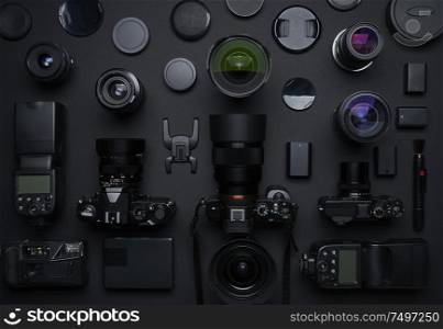 Flat lay top view of many various unknown brand camera,lens and photography equipment on black background .