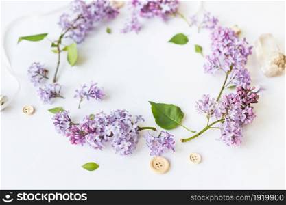Flat lay top view photo of spring composition. Wreath made of lilac flowers on white background. Summery floral frame.. Wreath made of lilac flowers on white background.