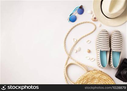 Flat lay traveler accessories on white background with straw hat, summer shoes, camera, bag and sunglasses. Top view travel or vacation concept. Summer background.