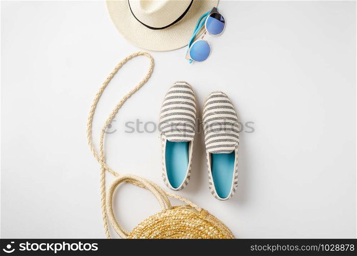 Flat lay traveler accessories on white background with straw hat, summer shoes, bag and sunglasses. Top view travel or vacation concept. Summer background. Space for text