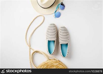 Flat lay traveler accessories on white background with straw hat, summer shoes, bag and sunglasses. Top view travel or vacation concept. Summer background. Space for text