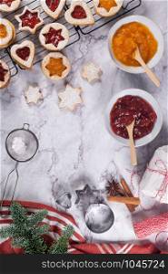 Flat lay with christmas cookies on marble surface with christmas decorative pine branch, jam, gift and cookie cutters