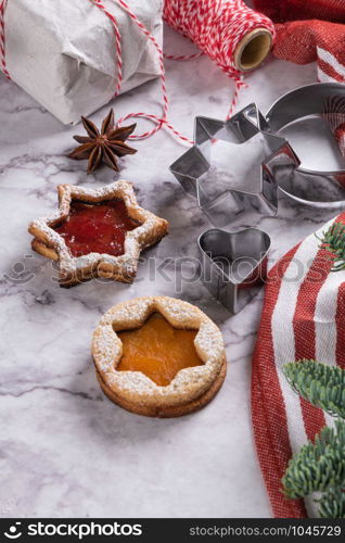 Flat lay with christmas cookies on marble surface with christmas decorative pine branch, jam, gift and cookie cutters