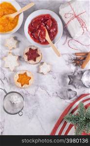 Flat lay with christmas cookies on marble surface with christmas decorative pine branch, jam, gift and cookie cutters