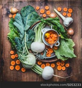 Flat lay with Fresh seasonal organic local vegetables for healthy clean eating and cooking on rustic wooden background, top view, place for text. Vegan or vegetarian food concept
