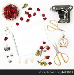 Flat lay with photo album, red rose petals, vintage camera, scissors on white background. Mock up sketchbook flowers