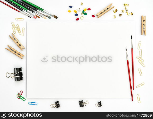 Flat lay with sketchbook, brushes, paper, office supplies on white background. Top view