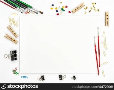 Flat lay with sketchbook, brushes, paper, office supplies on white background. Top view
