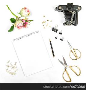 Flat lay with sketchbook, flowers, vintage photo camera, office tools on white background