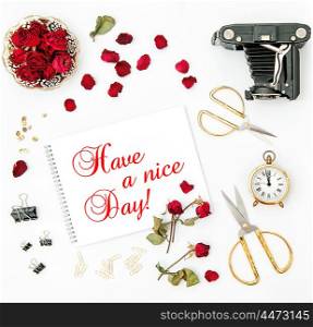 Flat lay with sketchbook, red rose, vintage camera, scissors on white background. Red flowers. Have a nice Day!