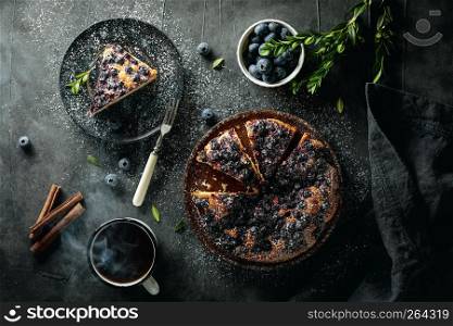 Flat lay with sliced homemade blueberry pie on dark background