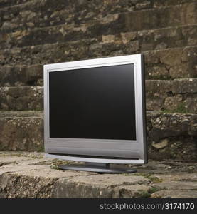 Flat panel television set in front of gray brick wall.