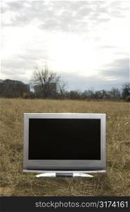 Flat panel television set in grassy field.