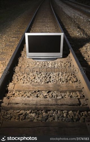 Flat panel television set on railroad tracks at night.