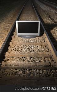Flat panel television set on railroad tracks at night.