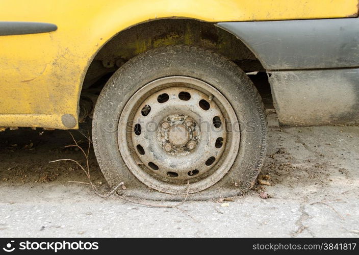 Flat tire of old yellow car on the parking