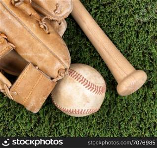 Flat view of old baseball mitt, ball and bat on grass