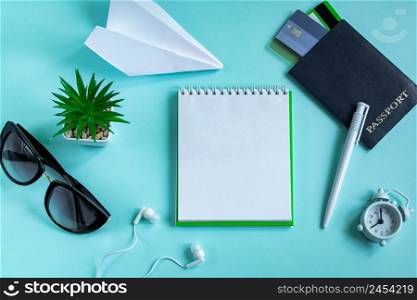 Flatlay travel accessories on a blue background. Summer vacation concept. Passport, credit cards, sunglasses, headphones, and a traveler’s notebook. Copy space.. Flatlay travel accessories on a blue background. Summer vacation concept. Passport, credit cards, sunglasses, headphones