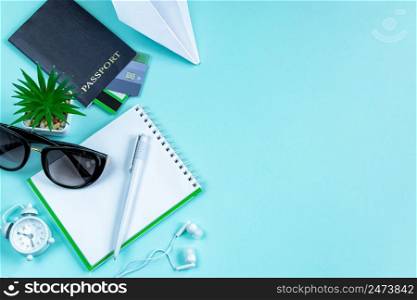 Flatlay travel accessories on a blue background. Summer vacation concept. Passport, credit cards, sunglasses, headphones, and a traveler&rsquo;s notebook. Copy space.. Flatlay travel accessories on a blue background. Summer vacation concept. Passport, credit cards, sunglasses, headphones
