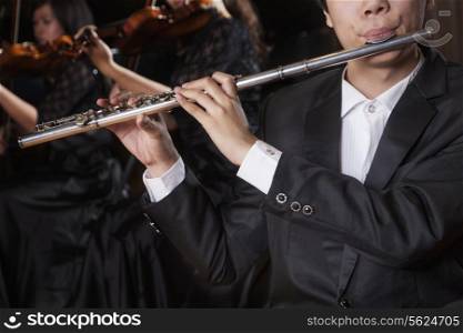 Flautist holding and playing the flute during a performance, close-up