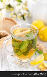 Flavored herbal tea with fresh lemon, ginger and mint leaves on white background, closeup