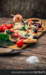 flavorful homemade pizza with bacon. hunk of delicious meat pizza with bacon and olives on the background of the vegetables.The image is tinted