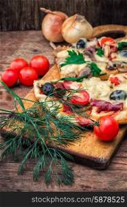 flavorful homemade pizza with bacon. hunk of delicious meat pizza with bacon and olives on the background of the vegetables.The image is tinted