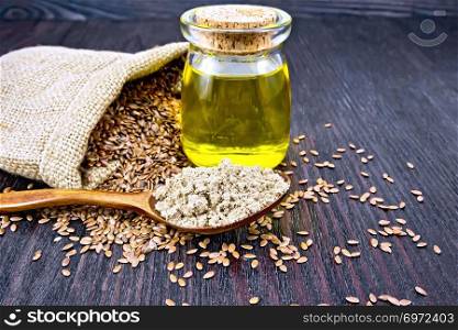 Flax flour in a spoon, oil in a glass jar, linen seeds in a bag and on a table on a wooden board background