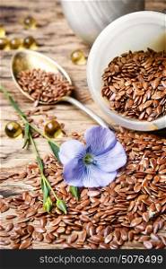 Flax seeds in spoon. Spoon with flax seeds and capsules with linseed oil